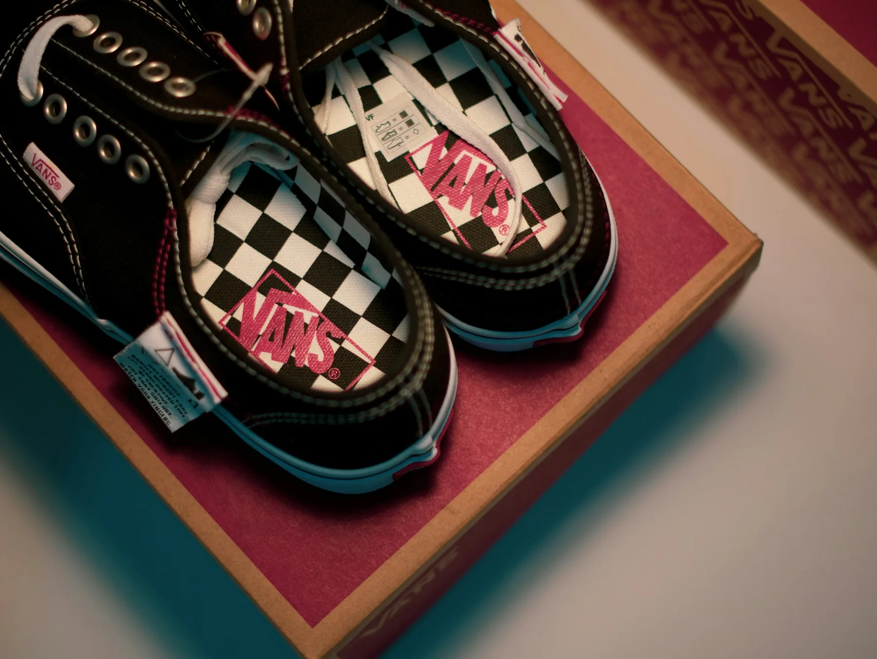A pair of black and white checkerboard skate shoes resting on top of their open shoe box